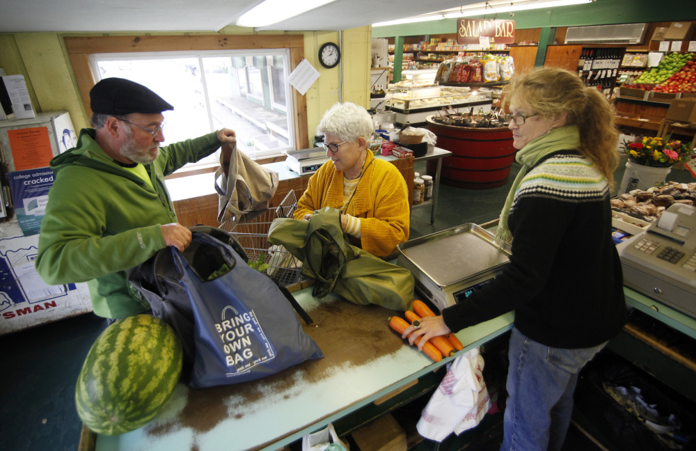 Victoria Simon, center, and her husband, Michael Modern, they check out at the Golden Harvest in Kittery, assisted by cashier Ashley Kehrig.