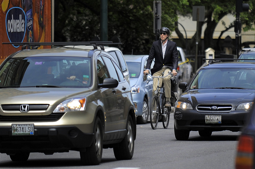 Bicyclists like this commuter on Congress Street in Portland will be subject, as will motorists, to a new Maine law taking effect Oct. 19 that could increase tickets that police issue for violations.