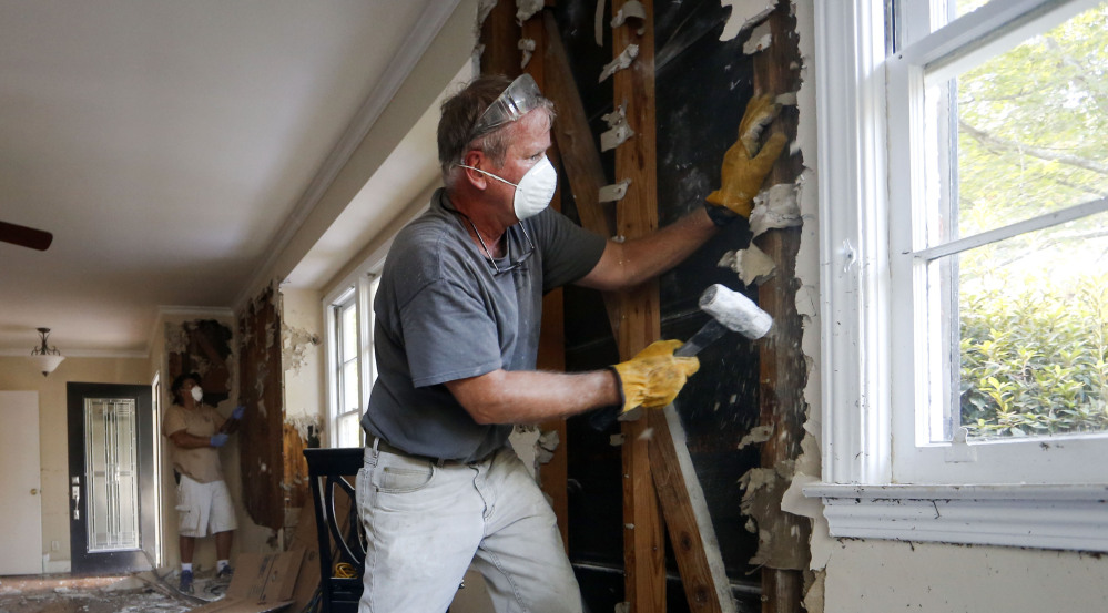 Bryan Allen works to remove wet drywall from a friend’s flood-damaged home Thursday in Columbia, S.C. It could take until the weekend for the threat of flooding to ease.