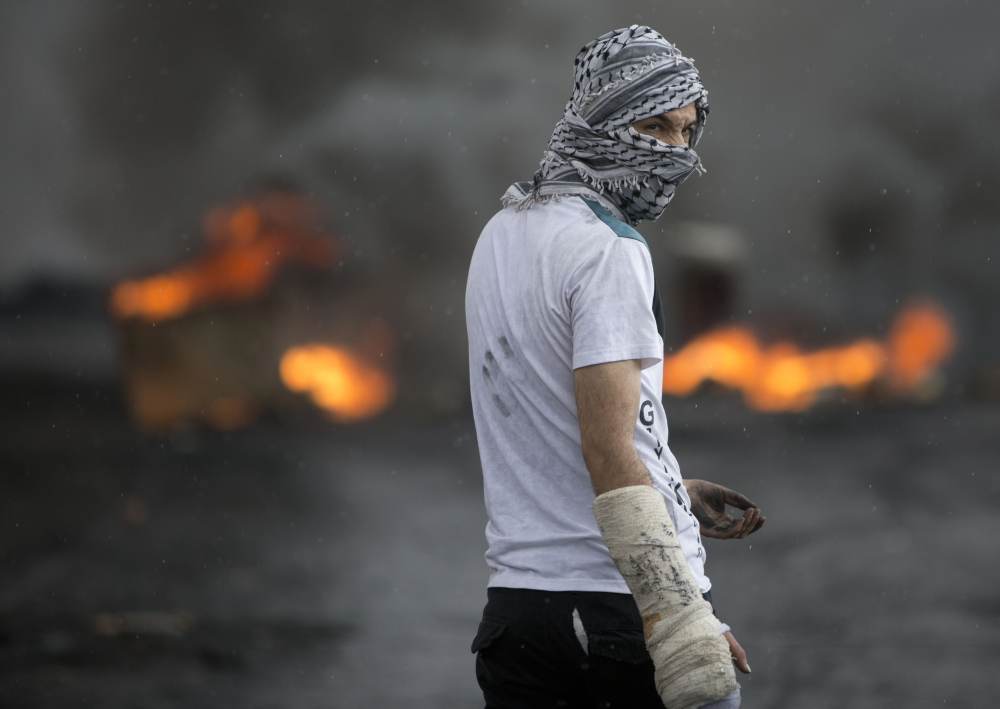 A Palestinian stands amid smoke from burning tires during clashes with Israeli troops near Ramallah on Thursday.