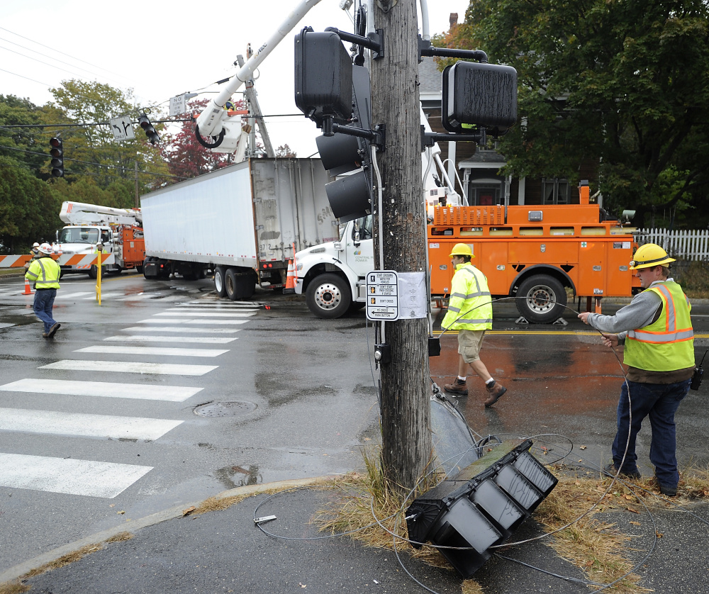 PORTLAND, ME - OCTOBER 9: Workers remove and contain the traffic lights that fell after a semi-tractor trailer truck snapped off at the corner of Brighton and Stevens Avenues. (Photo by Gordon Chibroski/Staff Photographer)