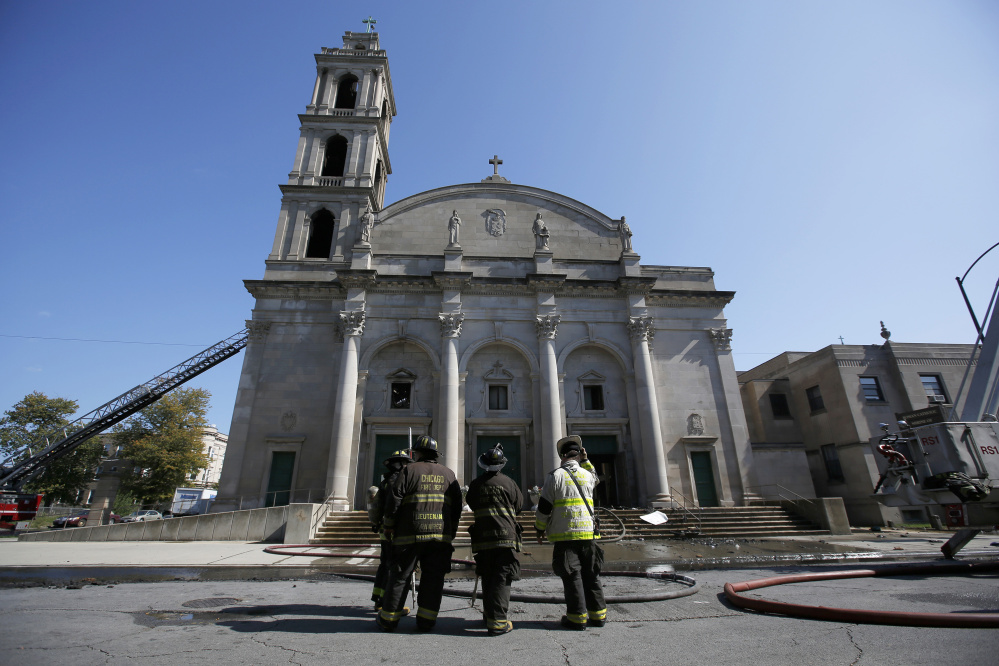 Chicago firefighters pause outside the Shrine of Christ the King Church in the city’s Woodlawn area after an extra-alarm fire Wednesday caused extensive damage. Dozens of women and children were evacuated from the shelter next door.
