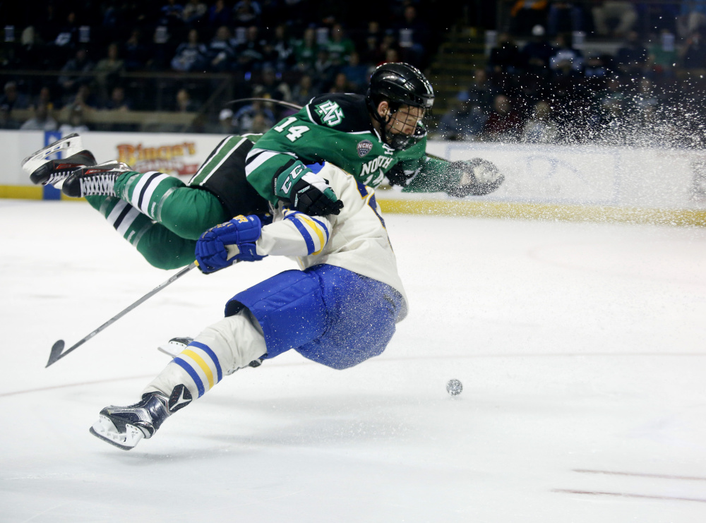 Austin Poganski of North Dakota gets upended by Owen Headrick of Lake Superior State during the second period of Friday’s game at the Cross Insurance Arena. Shortly after this play, Poganski scored to give North Dakota a 3-2 lead.