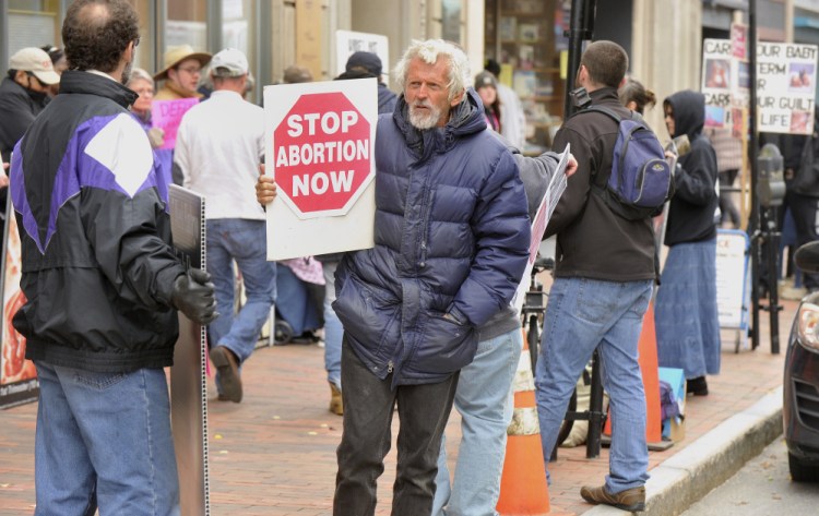 About 35 abortion opponents lined up outside the Planned Parenthood office at 443 Congress St. on Saturday to call for an end to the public funding of the organization.