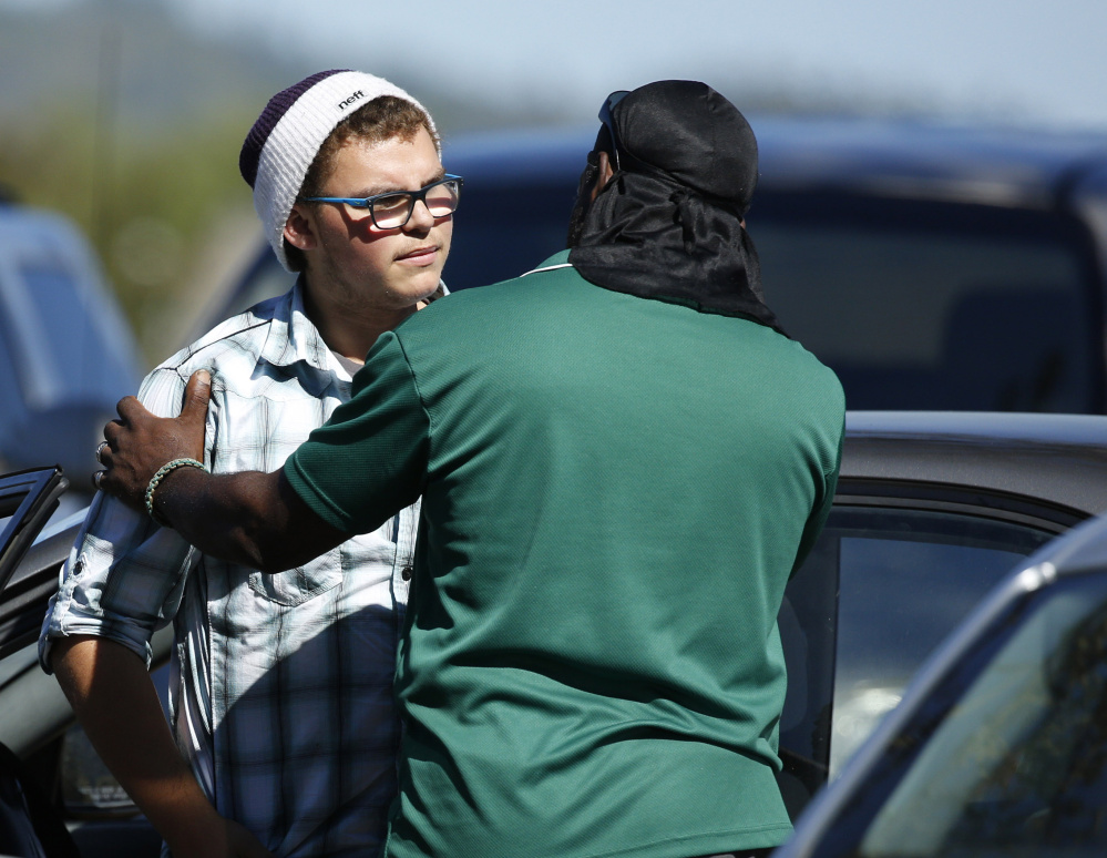 Student Mathew Downing, left, is comforted by an unidentified man Monday as they return to Umpqua Community College in Roseburg, Ore.
