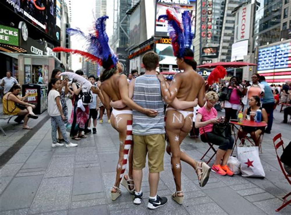 A tourist poses for a photo with two women clad in thongs and body paint in New York’s Times Square. Topless women posing for photos in Times Square are causing headaches for politicians and law enforcement who wish to regulate their presence but have no clear idea how.