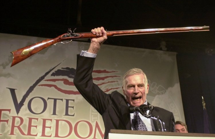 National Rifle Association President Charlton Heston holds up a rifle as he addresses gun owners during a “get-out-the-vote” rally in Manchester, N.H., in October 2002.