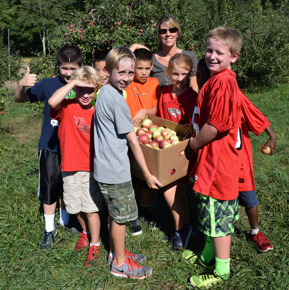 Wells Elementary School teacher Melissa Stapleton and students carry one of the boxes of apples they harvested at Spiller Farm in Wells as part of Farm to School Week.