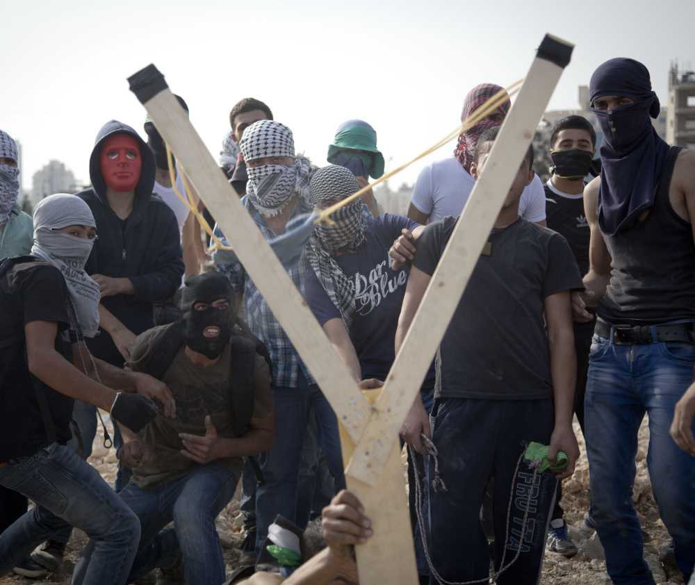 Palestinians use a large handmade slingshot to hurl a stone during clashes with Israeli troops near Ramallah in the West Bank on Monday. Recent weeks have seen a series of stabbing attacks in Israel and the West Bank.
