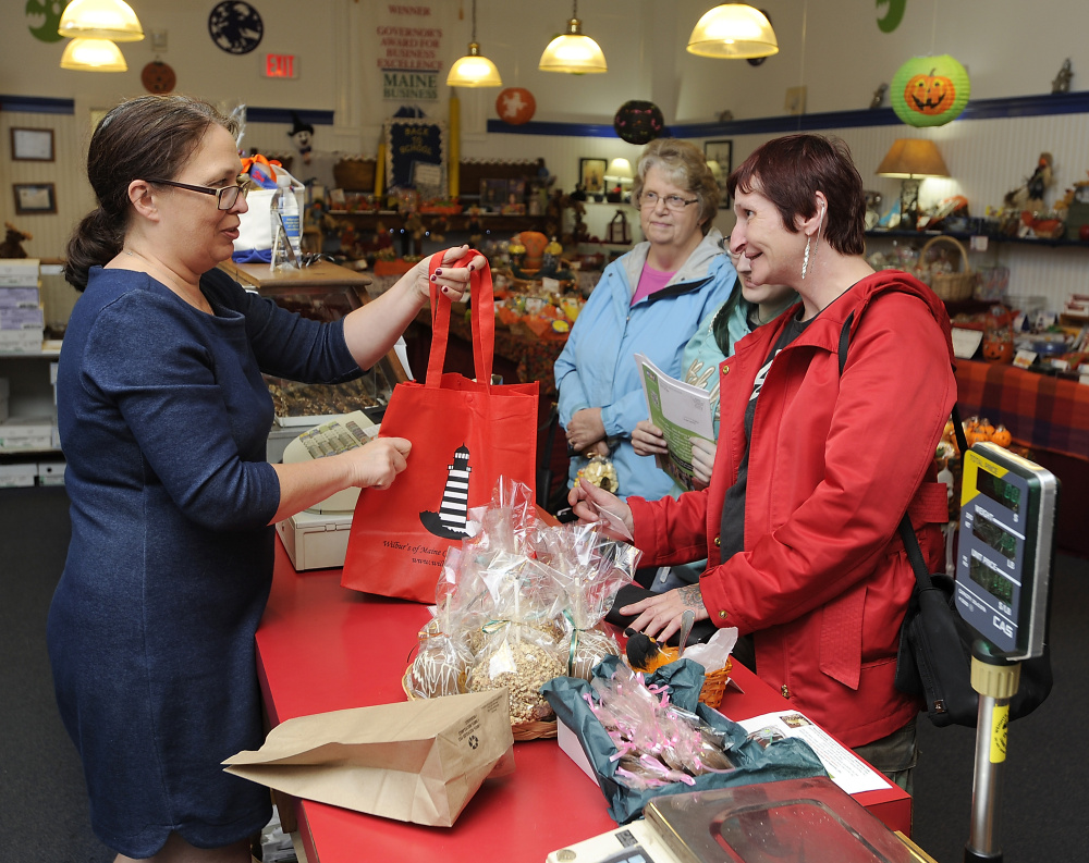 Clerk Lorraine Johnstone fills Freya Colella’s reusable bag at Wilbur’s of Maine Chocolate Confections in Brunswick. Colella favors less plastic pollution but not more regulation.
