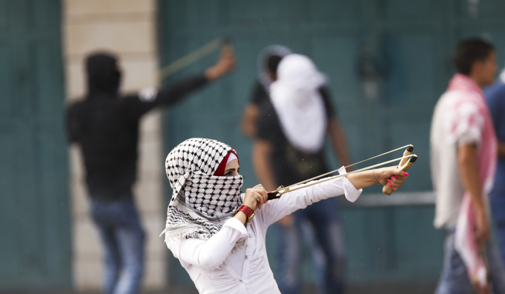 A Palestinian woman uses a slingshot during clashes with Israeli troops in the West Bank city of Bethlehem on Tuesday.