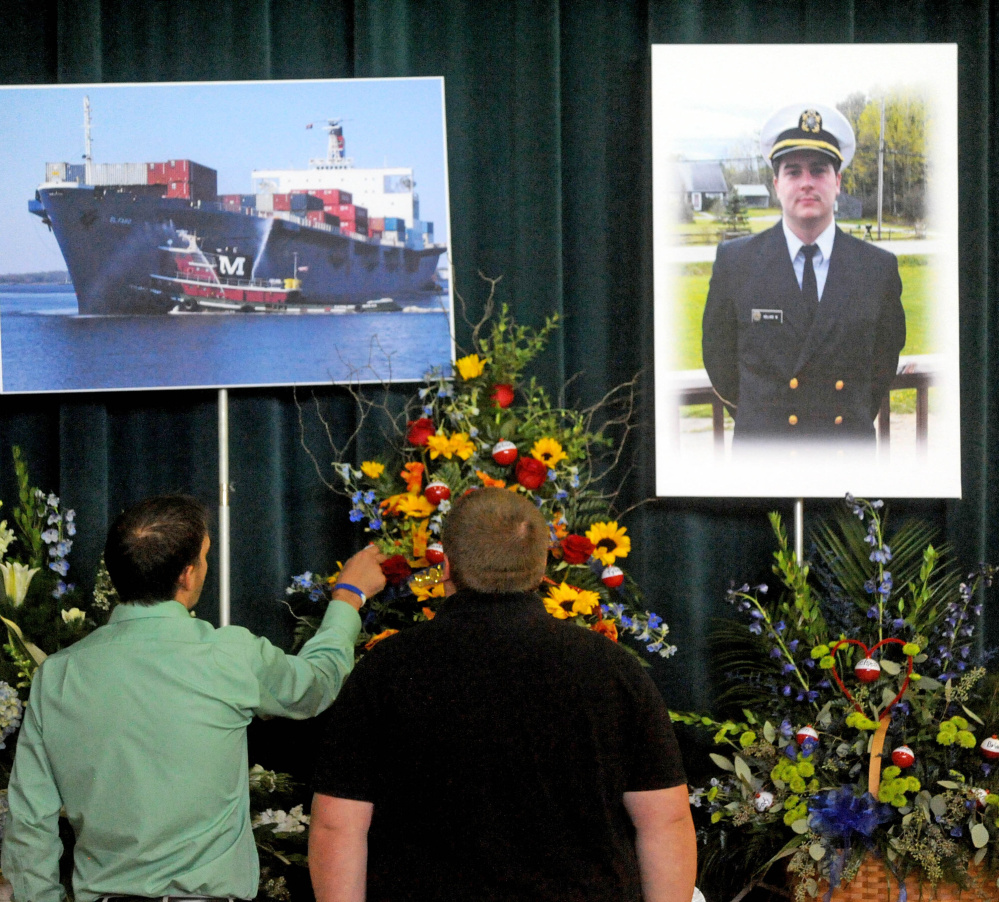 Friends and family pay their respects before a picture of Michael Holland and the cargo ship he worked on during a celebration-of-life ceremony at the Jay Community Building on Wednesday.