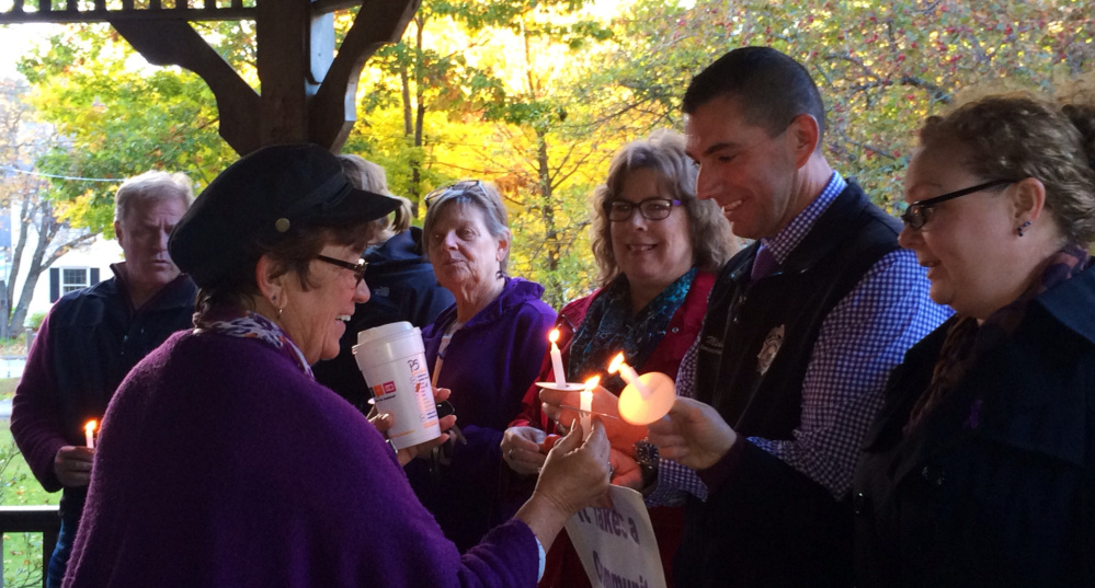 Kathleen Dumont, left, of Kennebec Valley Behavioral Health, lights a candle for Somerset County Sheriff’s Office investigator Mike Pike and others at a vigil Wednesday.