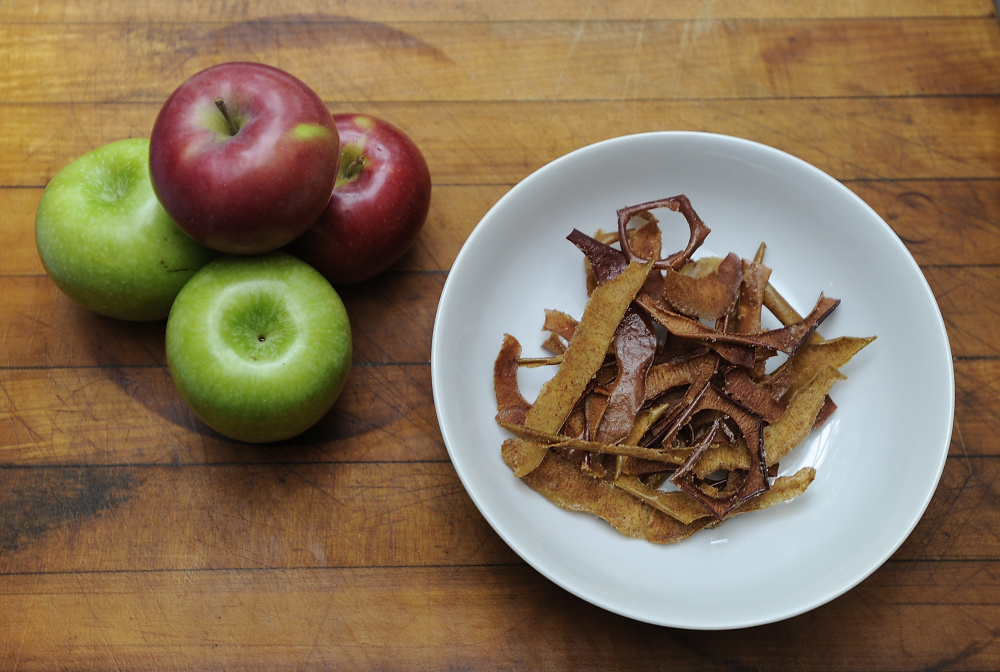 Green Granny Smith and red Macintosh apples sit alongside finished spiced apple peels.