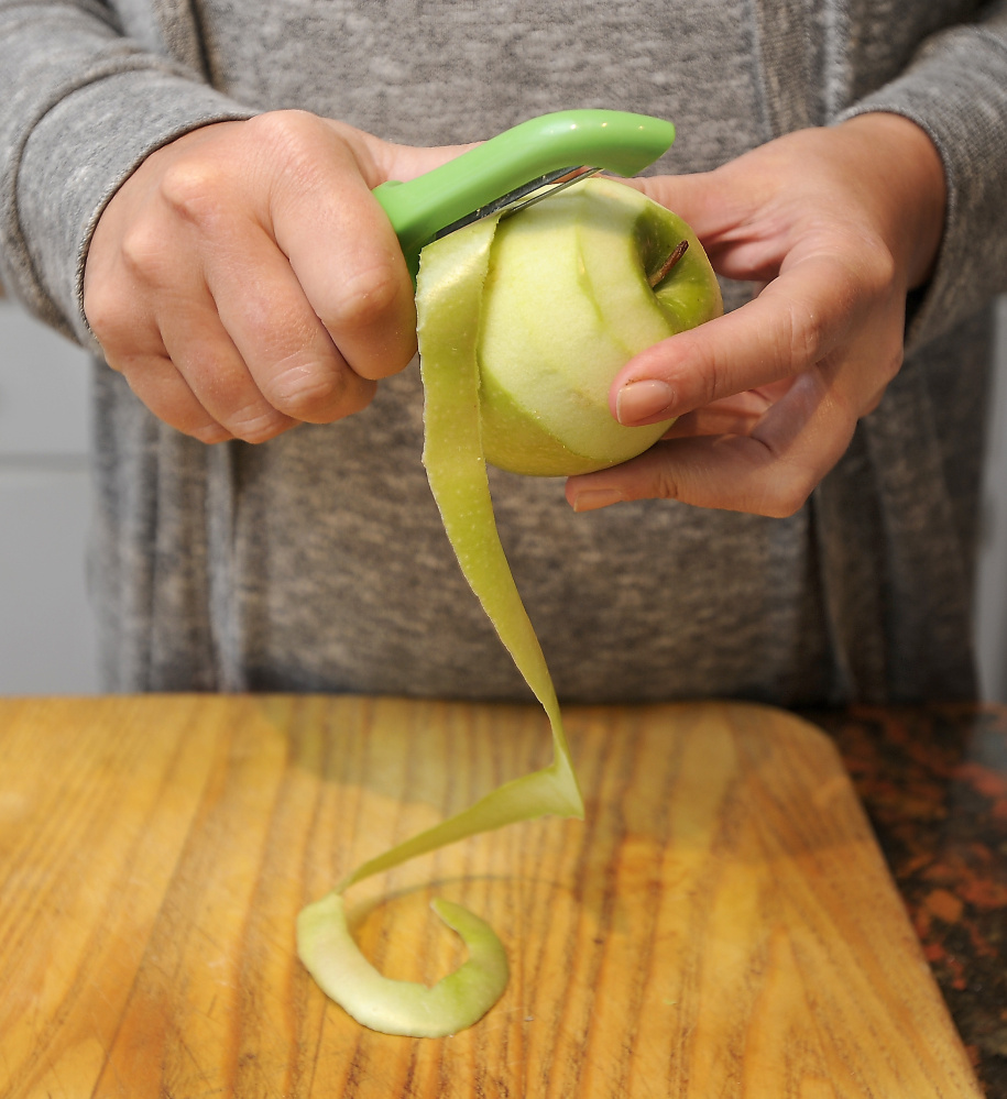 Taking a page from her great-grandmother Mabel, Christine Burns Rudalevige removes a long strip of peel from a Granny Smith apple destined for pie. The peel won’t go to waste – spiced, then crisped in the oven, it makes a great snack.