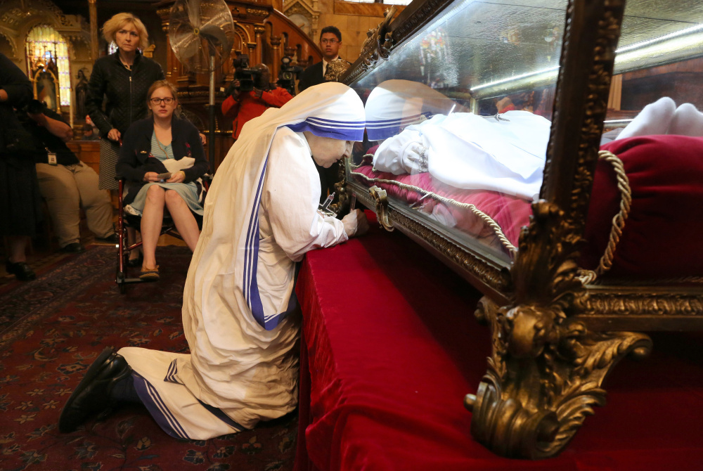 The faithful wait as one prays beside the casket of St. Maria Goretti at St. John Cantius Church in Chicago on Monday. After being stabbed to death while resisting a sexual assault at age 11, the saint is believed to have appeared to her killer.