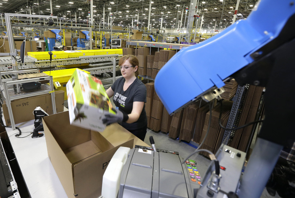 A worker places an item in a box for shipment at the Amazon.com fulfillment center in DuPont, Wash. The center is one of 50 around the country and three in the Puget Sound area that process and ship Amazon customer orders using a mix of robotic technology and human employees.
