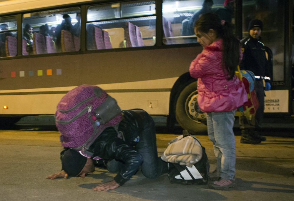 A man kisses the ground after getting off a bus in Lendava, Slovenia, on Saturday. Slovenian officials have said they can permit up to 2,500 migrants per day.