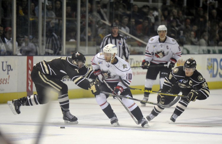 Rob Schremp of the Portland Pirates tries to carry the puck into the Hershey Bears’ zone Saturday night while defended by Ryan Stanton, left, and Garrett Mitchell. Portland’s first home opener as an affiliate of the Florida Panthers was a 3-2 victory before an announced crowd of 4,275.