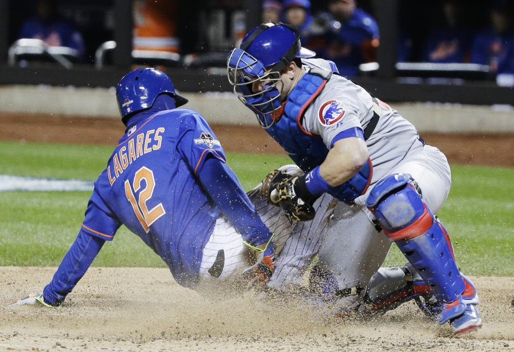 Mets center fielder Juan Lagares slides safely under the tag of Cubs catcher Miguel Montero in the seventh inning of Game 1 of the National League baseball championship series Saturday in New York. Lagares scored from third on a sacrifice fly by Curtis Granderson.