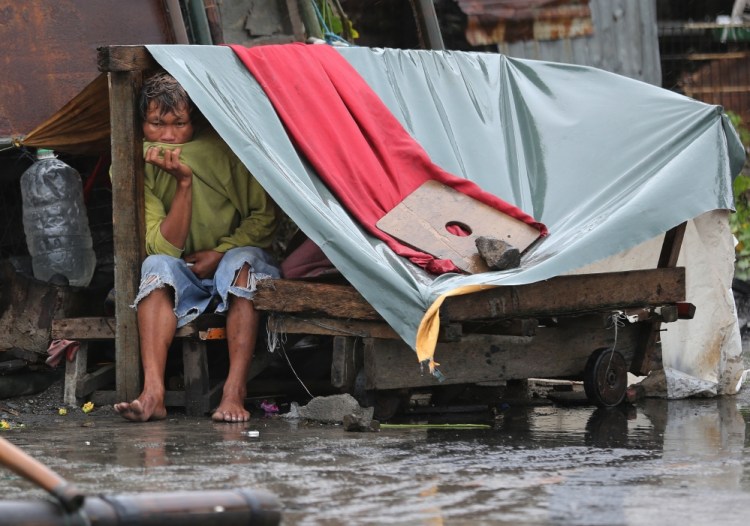 A Filipino man sits inside his makeshift home as strong winds and rains caused by Typhoon Koppu hit the coastal town of Navotas, north of Manila, on Sunday.