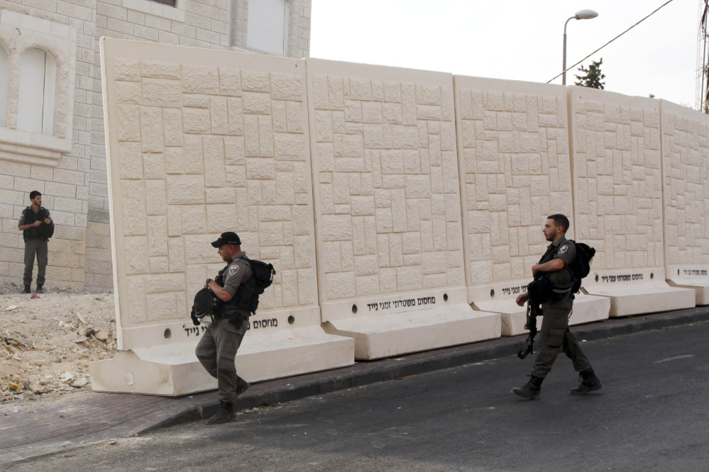 Israeli border police walk by a wall being built between Palestinian and Jewish neighborhoods in Jerusalem.