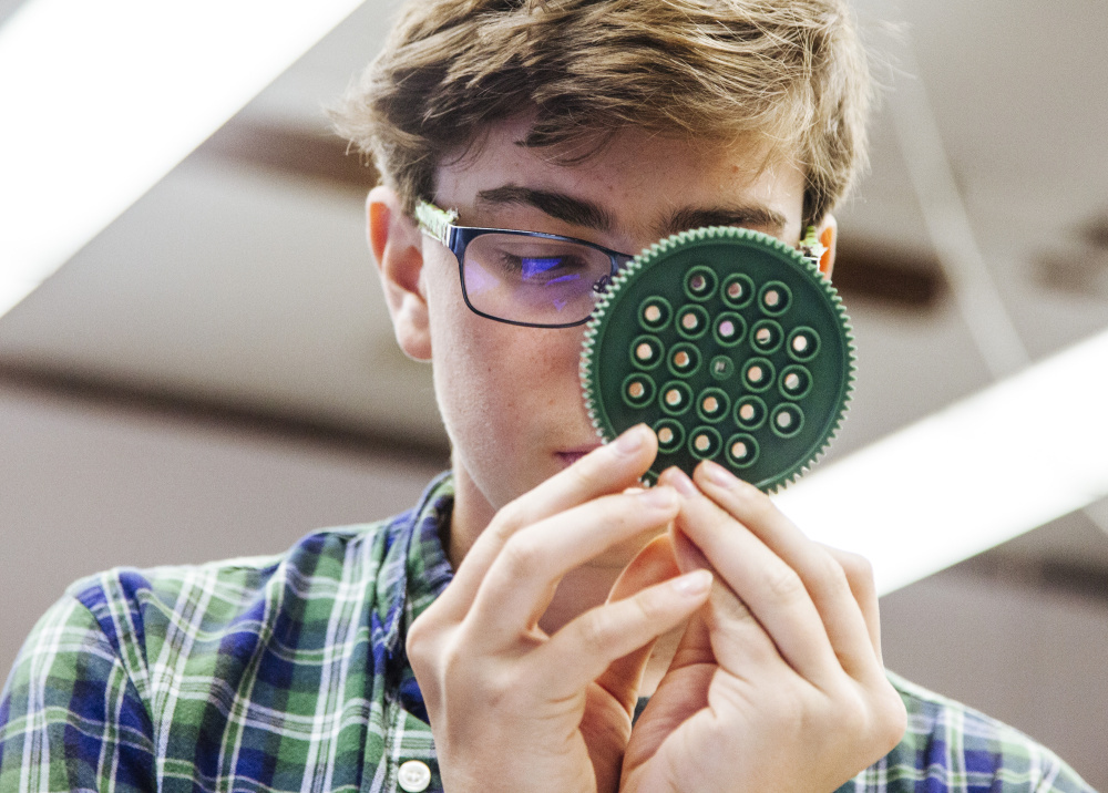 Freshman Hal Clews examines a gear to count its teeth during a small-group portion of his early college engineering class at Portland High School.