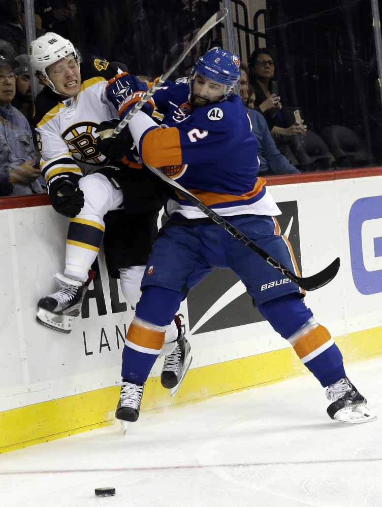 Islanders defenseman Nick Leddy checks Bruins wing David Pastrnak into the boards in the first period of Friday night’s game.