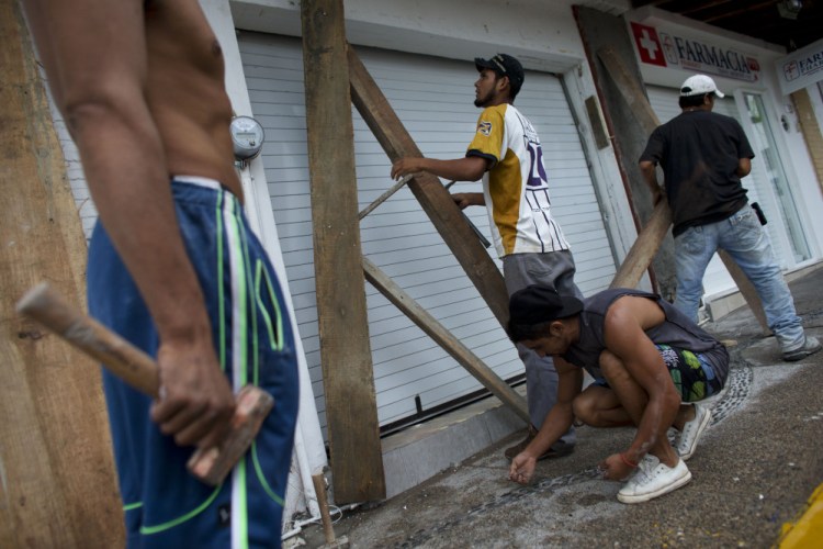Men remove protective wood beams from the front of a business the morning after Hurricane Patricia passed further south sparing Puerto Vallarta, Mexico, on Saturday.