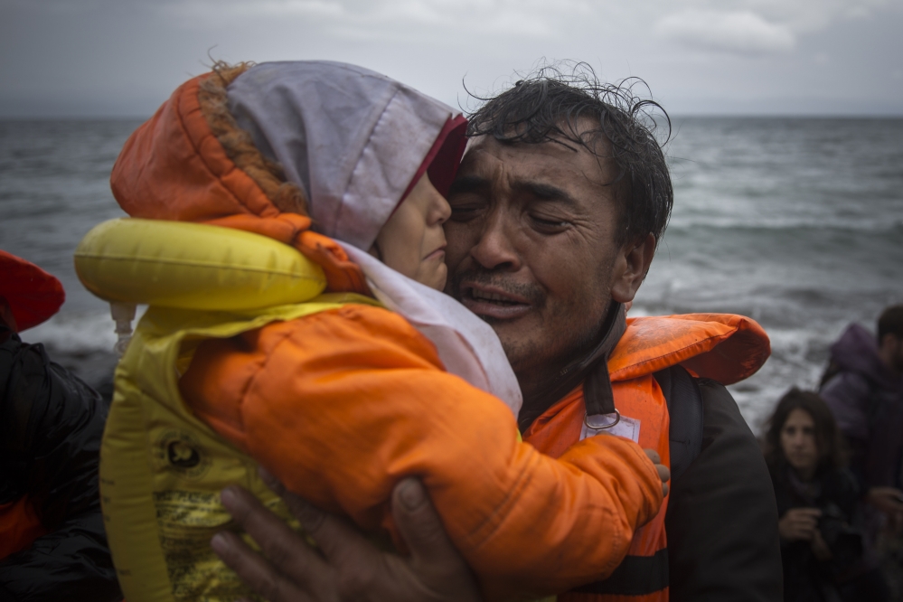 A man hugs a child after arriving Saturday with other migrants in a dinghy from Turkey to the Skala Sikaminias village on the northeastern Greek island of Lesbos.