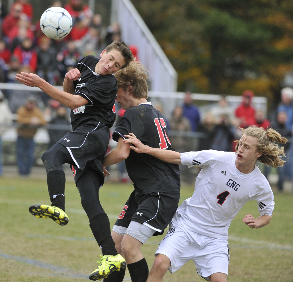 Gus Hunt of Lincoln Academy plays a high ball in front of teammate Nate Masters as Ben Rogers of Gray-New Gloucester is shielded off the play during Gray-New Gloucester’s 3-2 win Saturday.