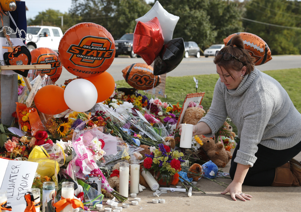 Stefanie Alexander, who witnessed the Saturday homecoming parade crash that killed four, places a candle at a makeshift memorial to the victims in Stillwater, Okla., on Monday.