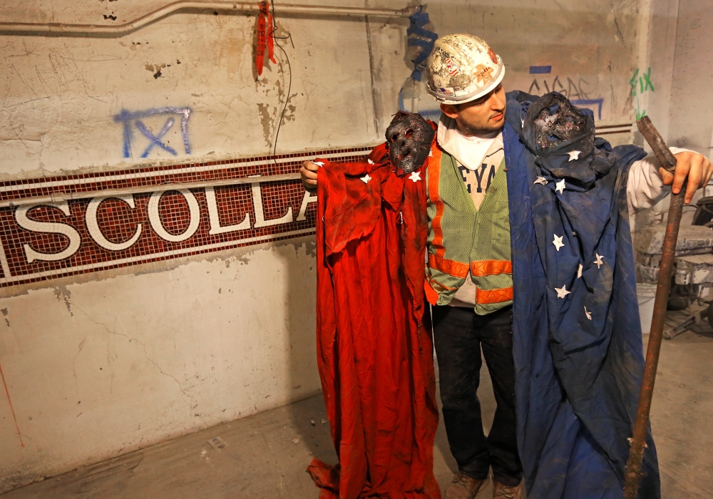 Steve Davis, a bricklayer working on the Blue Line, holds up two tattered rags fastened to bizarre masks at a Boston subway station on Tuesday. The garments were found balled up in a hollow section of concrete that was poured more than 60 years ago.
