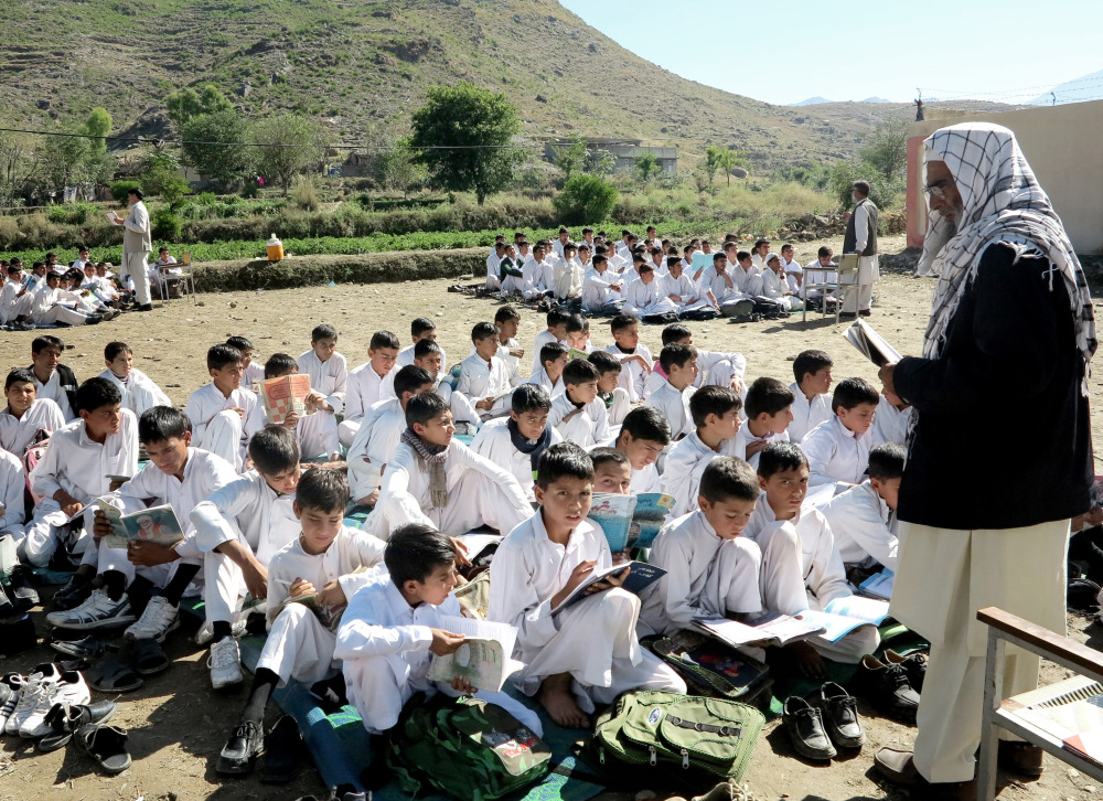 Students listen to their teacher in a field in Kabal, Pakistan, on Thursday. Their school was damaged by Monday’s earthquake, which was centered in nearby Afghanistan.