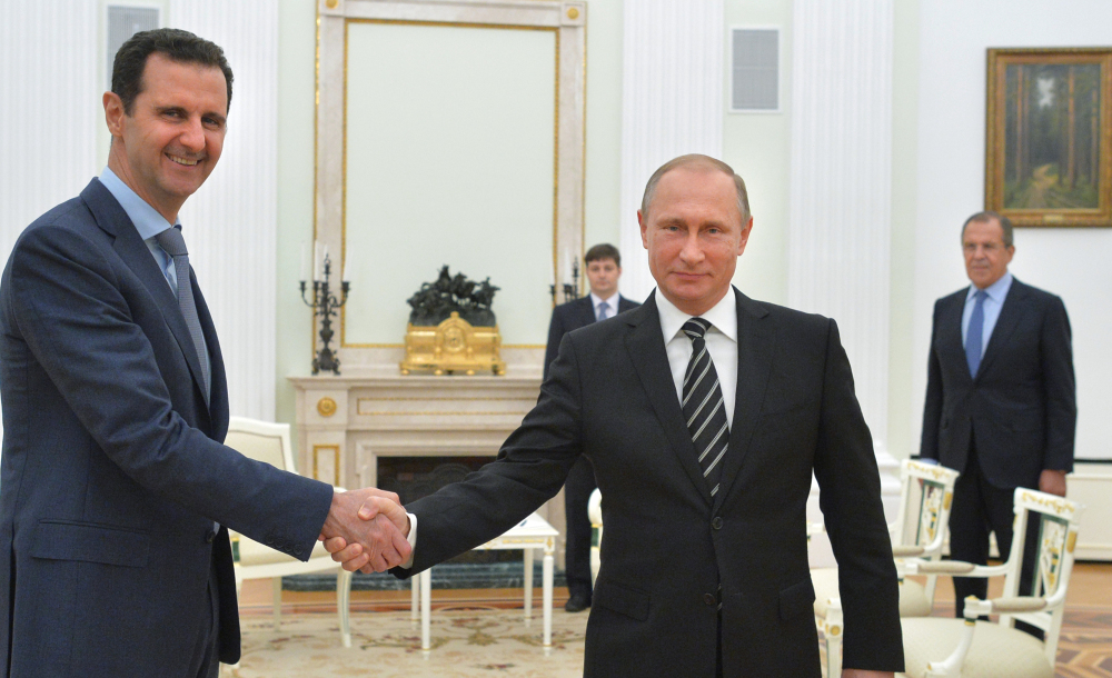 Russian President Vladimir Putin, center, shakes hands with Syrian President Bashar Assad in Moscow on Monday. But Assad is not attending negotiations in Vienna.