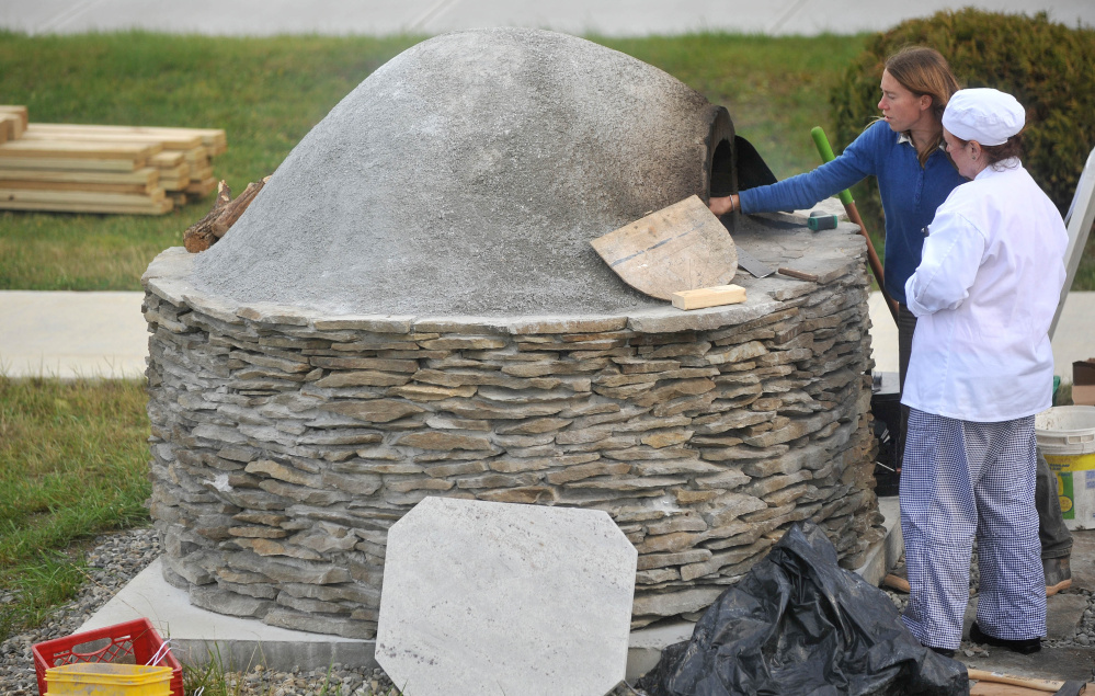 Katherine Creswell, right, farm manager at Kennebec Valley Community College, helps culinary student Brenda Madden with the wood-fired oven at the Alfond campus on Friday.