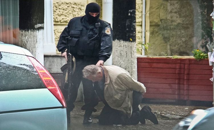 In this June 27, 2011, photo provided by the Moldova General Police Inspectorate, Teodor Chetrus is detained by a police officer in Chisinau, Moldova, during a uranium-235 sting operation. The Associated Press