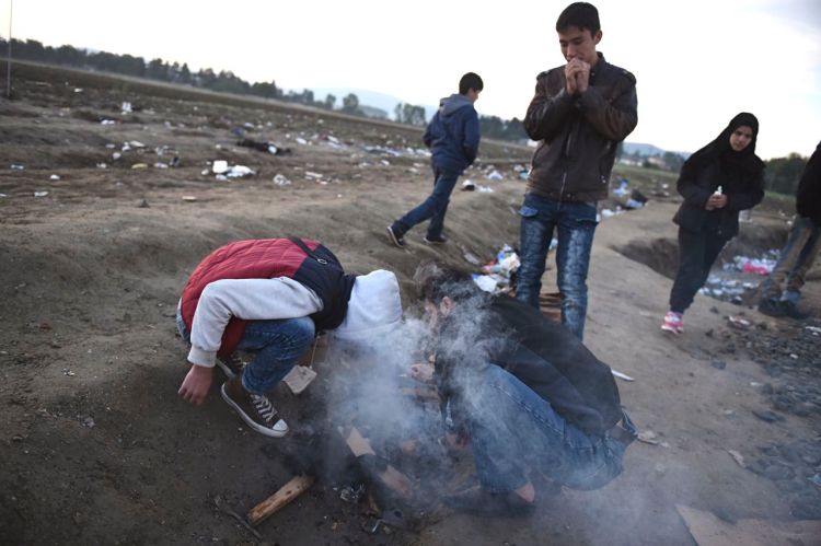 Migrants and refugees light a fire as they wait to pass from the northern Greek village of Idomeni to southern Macedonia, Monday. European leaders have decided that reception capacities should be boosted in Greece and along the Balkans migration route to accommodate 100,000 more people as winter looms. The Associated Press