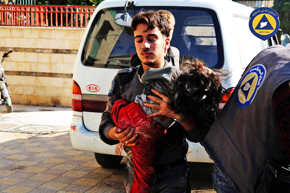 A paramedic holds a child who witnesses said was hit by Syrian government missiles Friday. The Syrian Observatory for Human Rights and the Local Coordination Committees group said government forces fired more than 11 missiles at the market, killing at least 40 people. Syrian Civil Defence via AP