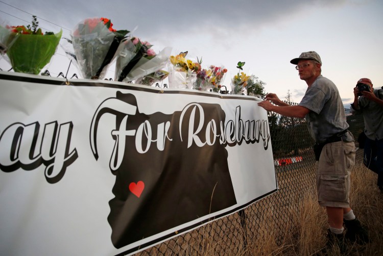 Michael Garwood places flowers Friday at a makeshift memorial near the road that leads to Umpqua Community College, in Roseburg, Ore. The small town is the latest U.S. community to experience the horror of a mass shooting.
The Associated Press