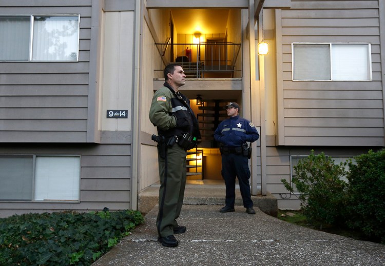Douglas County Deputy Sheriff Greg Kennerly, left, and Oregon State Trooper Tom Willis stand guard on Oct. 2 outside the apartment building where alleged Umpqua Community College gunman Chris Harper Mercer lived with his mother in Roseburg, Ore. The Associated Press