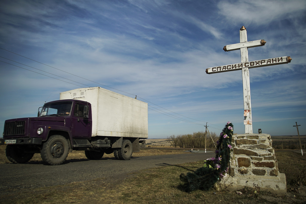 A truck drives by an Orthodox cross with a sign reading Save and Guard, at a memorial to the victims of the Malaysian Airlines MH17 plane crash,  near the village of Hrabove, eastern Ukraine, Tuesday Oct. 13. The Associated Press