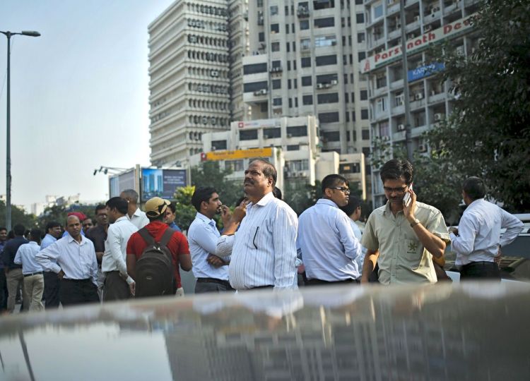 People stand on a road divider after vacating buildings during an earthquake in New Delhi, India, on Monday. (Reuters)