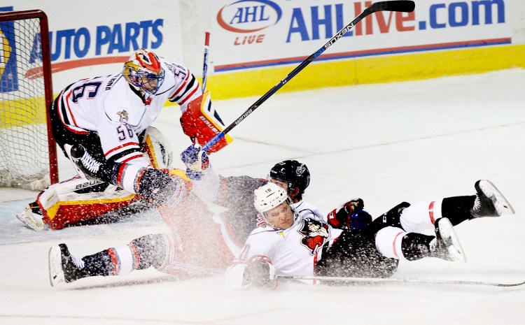 Rob Schremp of the Portland Pirates gets tangled up with Tanner Glass of the Hartford Wolf Pack in front of Portland goalie Mike McKenna during Portland’s 6-2 victory Wednesday night at the Cross Insurance Arena. Schremp was called for a penalty on the play. Shawn Patrick Ouellette/Staff Photographer