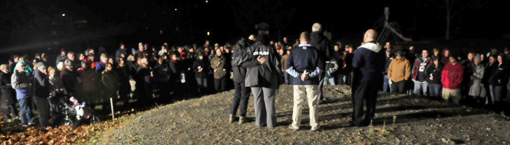 Members of the clergy and police lead a prayer with scores of people who attended a candlelight vigil at the boat landing for the three victims murdered last week in Oakland on Sunday.
