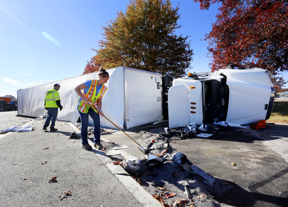 Franki Delaney of the Maine Department of Environmental Protection sweeps up after a tractor-trailer overturned at the northbound service plaza in Kennebunk off Interstate 95 on Monday.