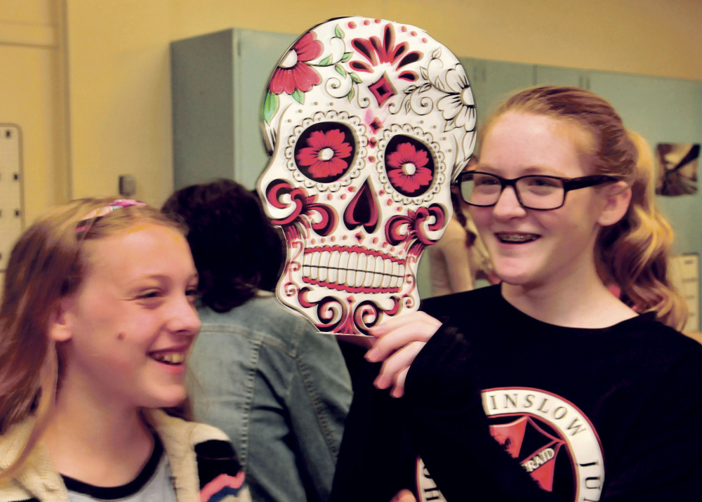 Winslow Junior High School students Katie Stevens, left, and Felicia Lessard have fun with a mask the Spanish class made for Day of the Dead on Monday.