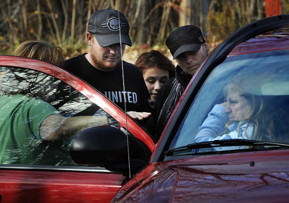Family members gather around a car to lend support to the wife of Mike Winslow Sr. of Poland, who refused to come out of his house following the report of a domestic disturbance.