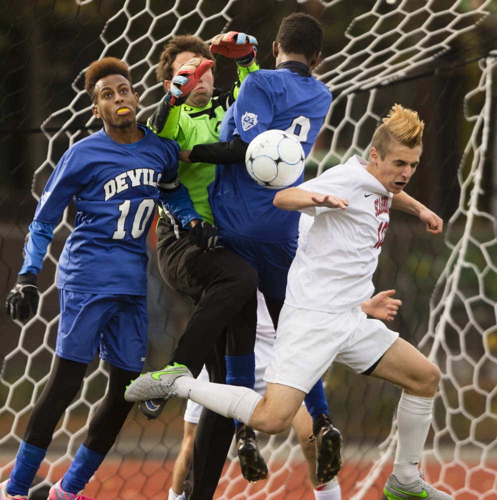 Lewiston goalie Austin Wing contends with heavy traffic while teammates Abdi Shariiff-Hassan, left, and Mohamed Khalid help to deny a threat by Noah Stracqualursi of Scarborough. The Blue Devils gave up seven goals in 18 games this season.