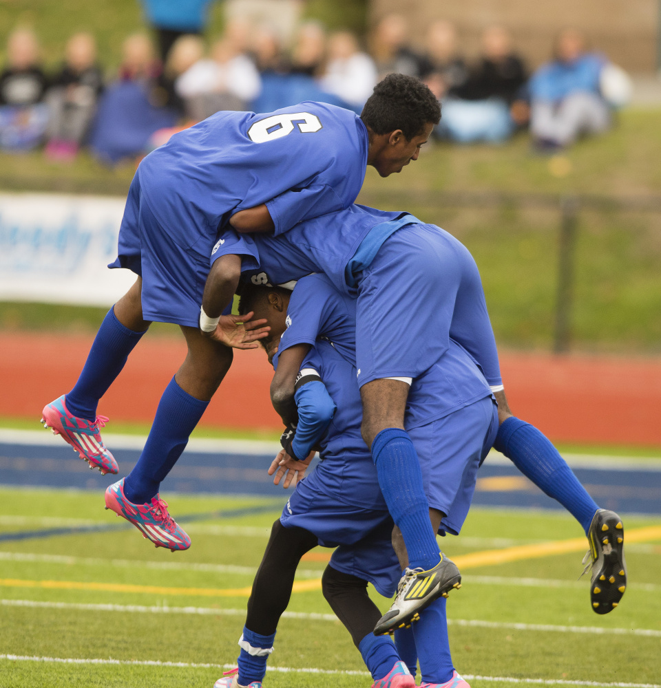 The Lewiston High players pile on Maulid Abdow, whose flip-style throw-in to the box created the scramble that led to an own goal that was the difference in the game.